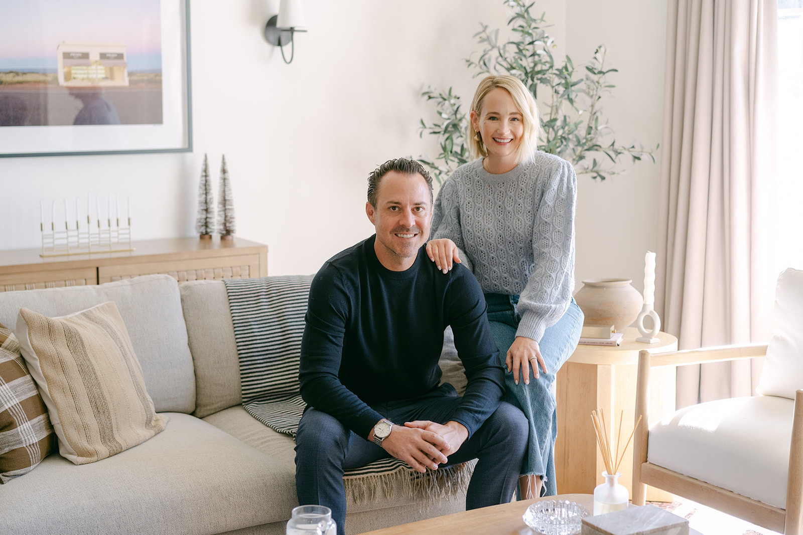 Ashley and Doug of DMF Realty seated together in a staged living room